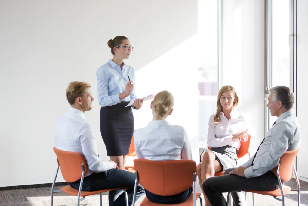 Führungskräftetraining – Trainerin unterrichtet Gruppe im Stuhlkreis